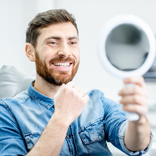man smiling holding a mirror