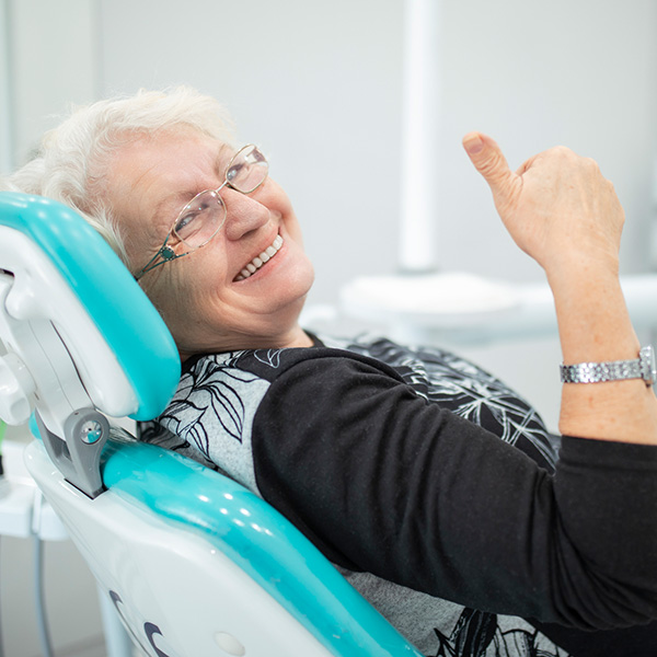 lady with thumbs up in a dental chair