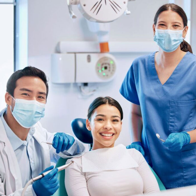 lady smiling in dental chair with dentists on either side